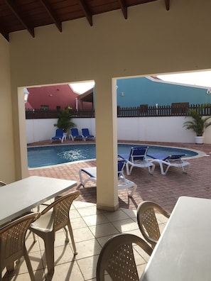 Relax by the pool surrounded by lush greenery and comfortable seating.