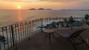 A balcony with a view of the sunset over the ocean, a table, and two chairs. -  Stunning ocean and one of Mazatlans top tourist attractions cliff divers view. (Mazatlán)