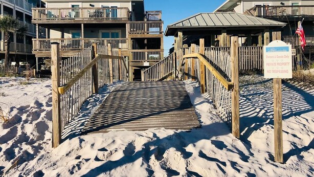 A wooden boardwalk leading to a beachfront property with multiple balconies and a sign indicating private property. - #404- 2 bed-1 bath sleeps 6- Fall beach getaway…& Winter Snowbirds! Book now! (Gulf Shores)