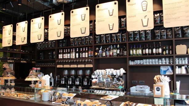 Un comptoir de café où sont présentées différentes sortes de café et une variété de pâtisseries.