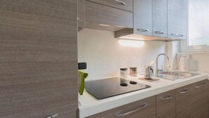 Une cuisine moderne avec des meubles en bois, un plan de travail blanc et des appareils électroménagers en acier inoxydable.