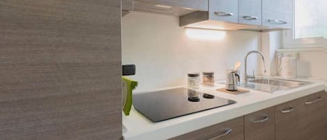 Una cocina moderna con armarios de madera, encimera blanca y electrodomésticos de acero inoxidable.