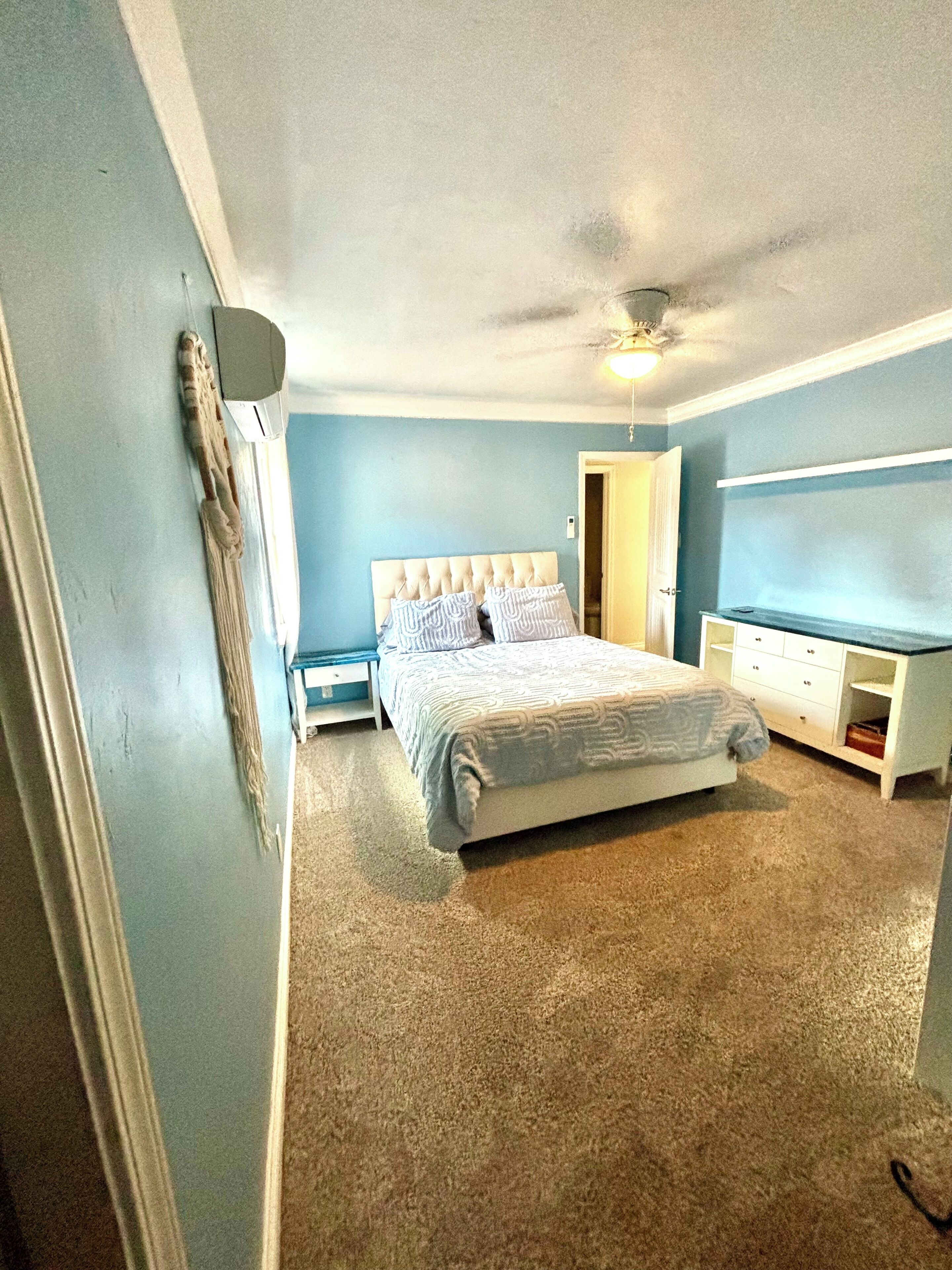 Une chambre à coucher avec un lit, une commode, un téléviseur et un ventilateur de plafond.