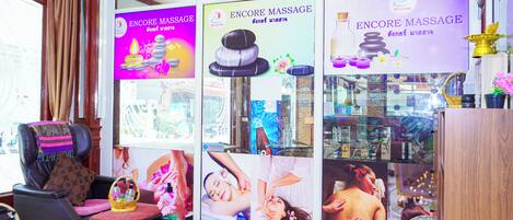 A massage parlor with multiple massage chairs, a reception area, and a display of massage products.