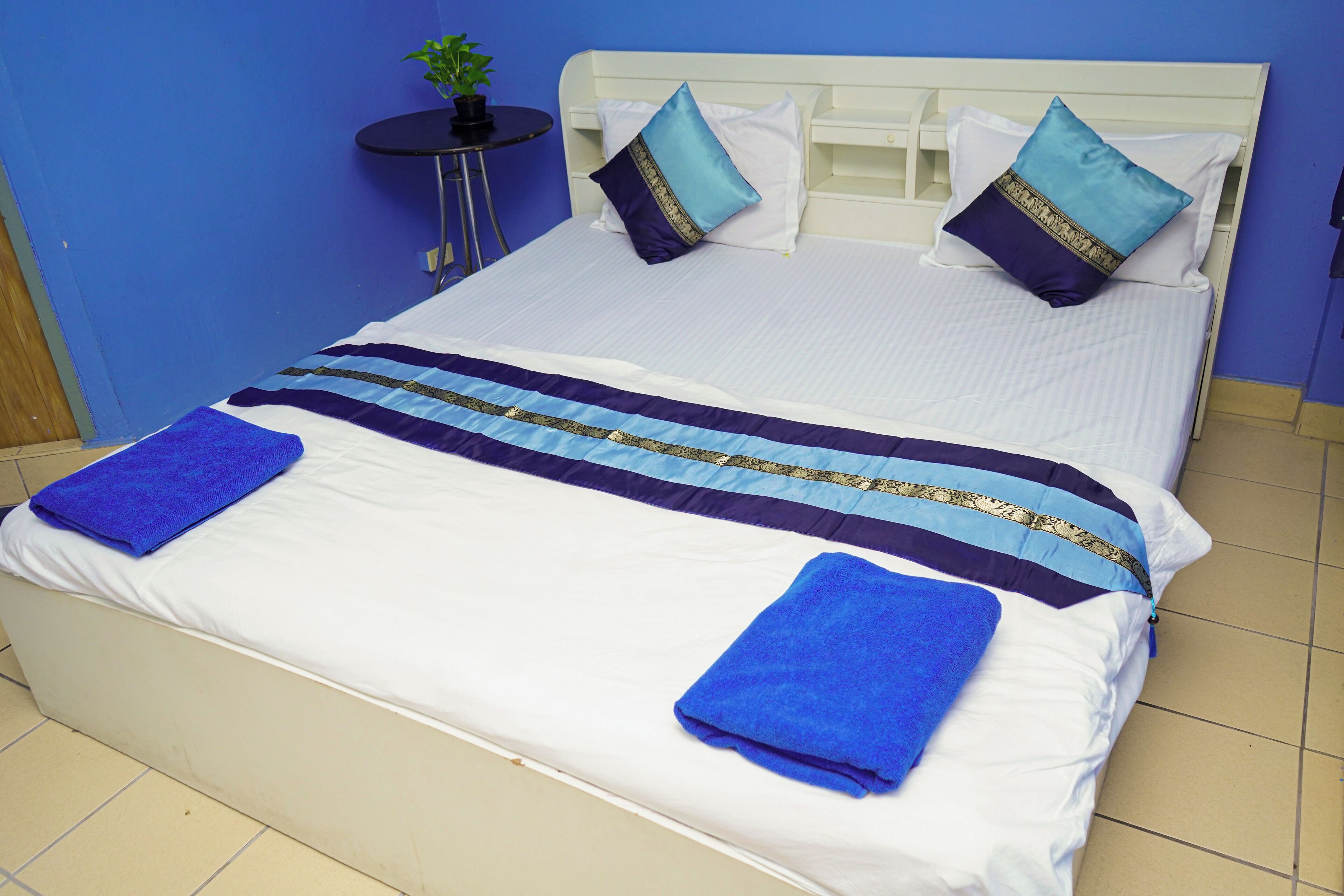 A bed with a white headboard, two pillows, a blue and white striped blanket, and two blue towels.