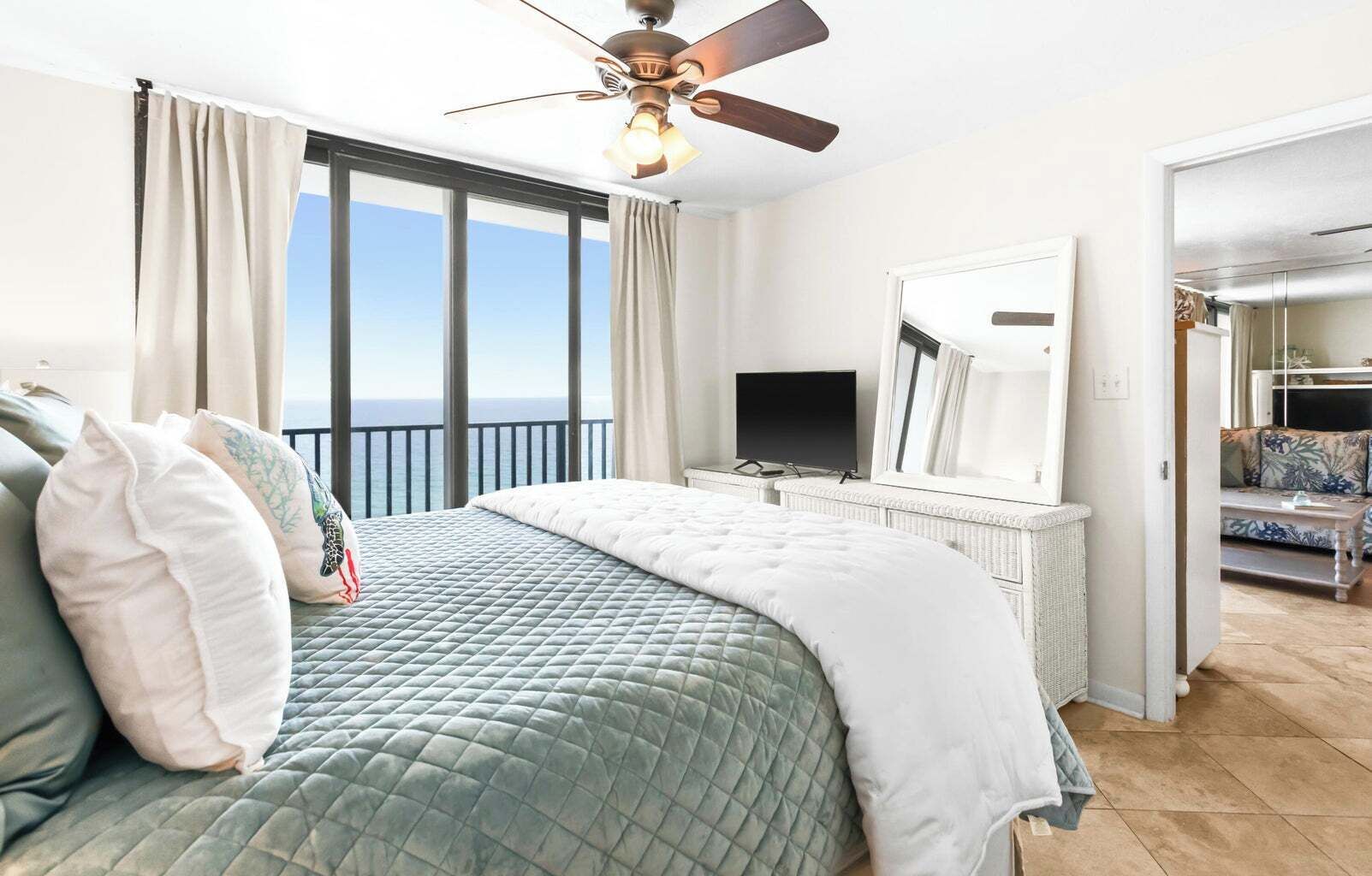 A hotel room with a bed, a television, a mirror, and a balcony with a view.