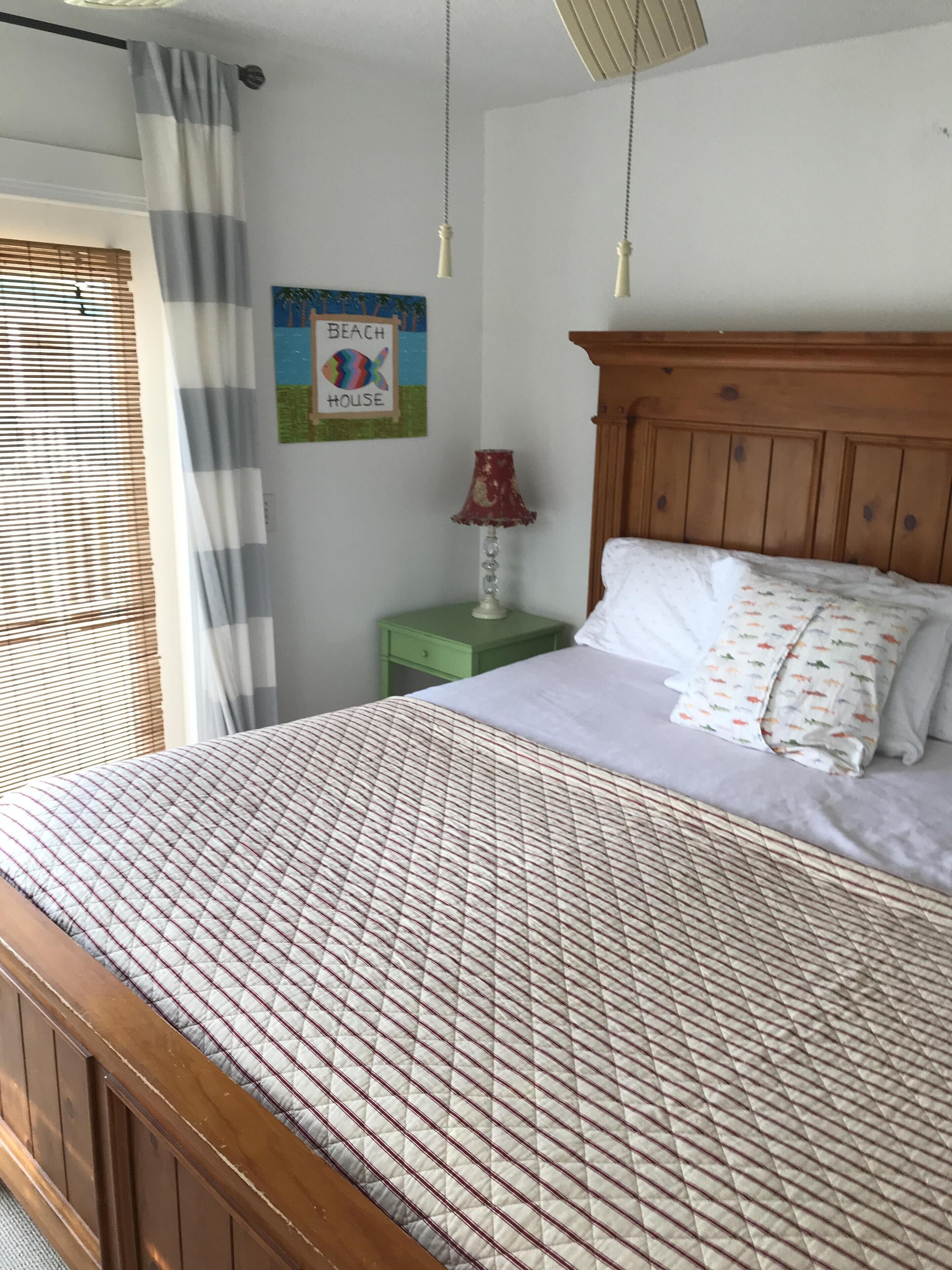A bedroom with a wooden bed, a green nightstand, a lamp, and a wall decoration.