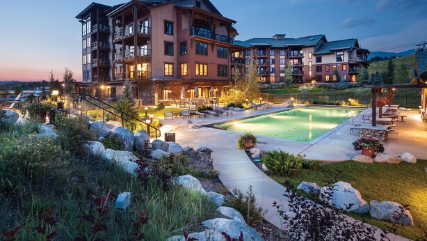 A multi-story hotel with a swimming pool, outdoor seating, and a well-maintained garden. - Top-Floor Luxury Condo with Panoramic Views at Trailhead Lodge! (Steamboat Springs)