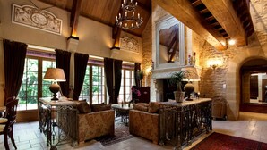 Un salón amplio con chimenea, muebles ornamentales y ventanas grandes.