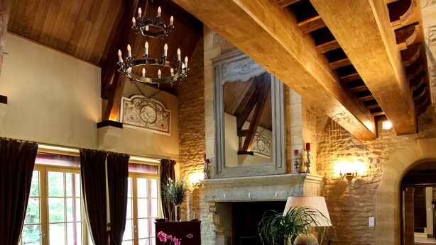 Amplia sala de estar con chimenea, vigas de madera y un candelabro.