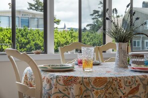 Een eettafel met stoelen, een vaas met bloemen en een glas amberkleurige vloeistof.