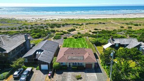 A residential area with houses, a lawn, and a beach in the background.