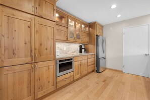 A kitchen with wooden cabinets, a stainless steel refrigerator, and a built-in oven.