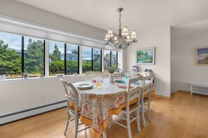 A dining area with a table set for four, large windows, and a chandelier.