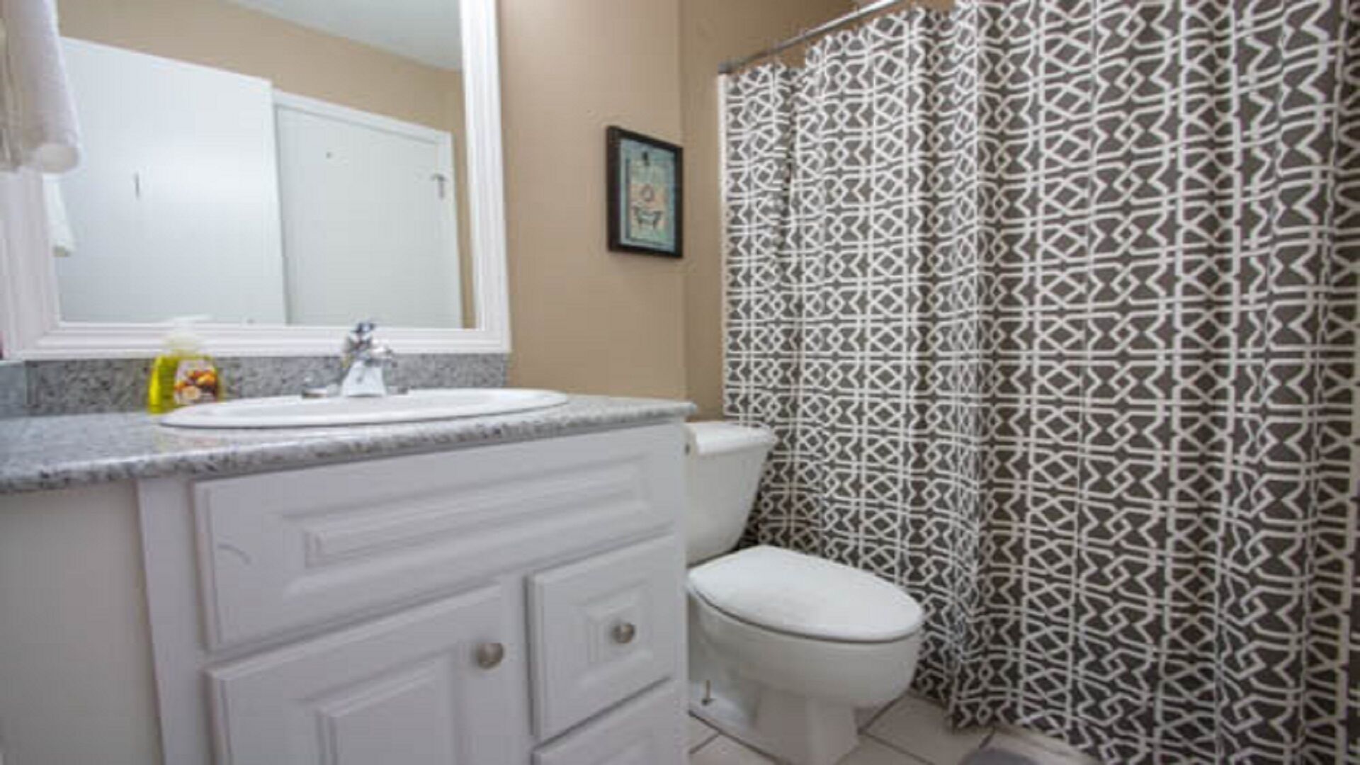 A bathroom with a white sink, vanity, and toilet.