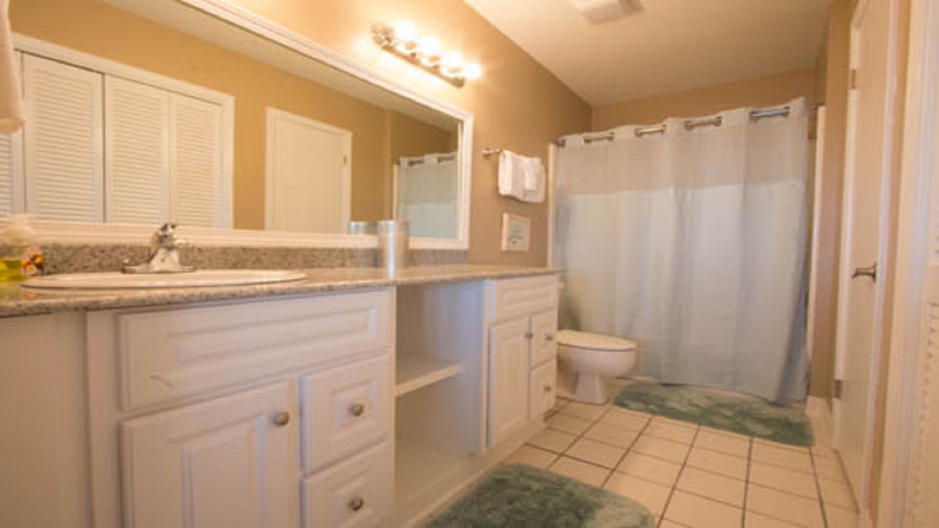 A bathroom with a sink, mirror, toilet, and shower curtain.