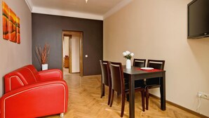 Un comedor con una mesa y sillas de madera, un sofá rojo y un cuadro en la pared.
