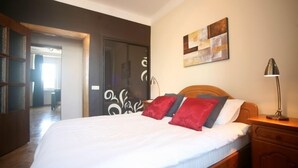 Un dormitorio con una cama de madera, una mesita de noche, una lámpara y una obra de arte en la pared.