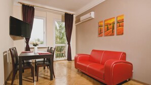 Una habitación con una mesa de comedor, sillas, un sofá rojo y tres cuadros en la pared.