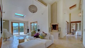 Ein geräumiger Wohnbereich mit einer großen Couch, einem Kamin und Blick ins Freie.