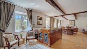 Ein geräumiger Raum mit einem großen Holzesstisch, einer Bar mit Spiegel und Blick ins Freie durch ein Fenster.