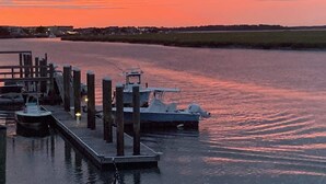 Un port de plaisance où des bateaux sont amarrés à des quais en bois, au coucher du soleil.