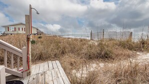 Une promenade en bois menant à une plage, avec une maison visible au loin.