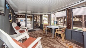 Un espace extérieur abrité, doté de sièges et d’une table, de grandes fenêtres et offrant une vue sur l’extérieur.