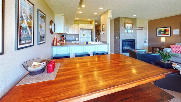 A modern kitchen with white cabinets, a wooden dining table, and a built-in stove. - OCEAN FRONT: DESTRESS RX: Seaside Vacation Homes, Inc Managed (Seaside)