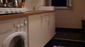 A compact kitchen with a washing machine, a stove, and a window with a view of a building at night. - 3 Double Bedroom, Right Next to Blue Mosque, on Akbiyik Street (Istanbul)