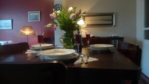 A dining table set with plates, cutlery, and glasses, with a vase of flowers and a lamp in the background. - 3 Double Bedroom, Right Next to Blue Mosque, on Akbiyik Street (Istanbul)