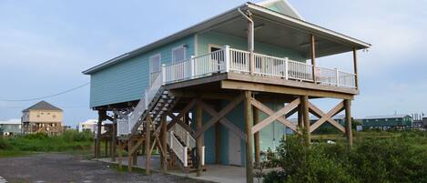 A two-story house with a balcony on the upper floor, wooden deck, and a staircase leading to the upper level.