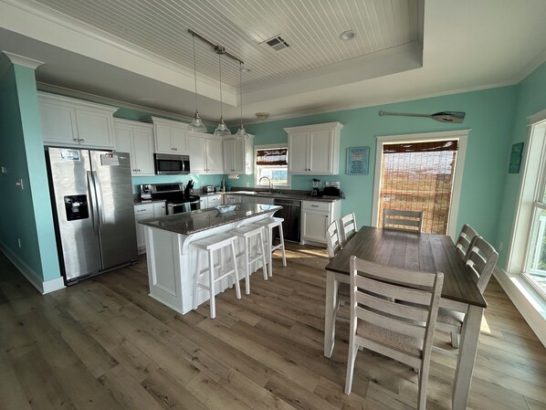 Una cocina moderna con armarios blancos, electrodomésticos de acero inoxidable y una isla central con taburetes de bar.