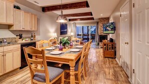Un comedor con una mesa de madera dispuesta para cuatro personas, rodeada de sillas de madera con cojines de cuadros.