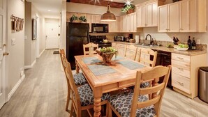 Una cocina moderna con armarios de madera, una isla central y un comedor con mesa y sillas de madera.