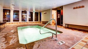 Una piscina con una escalera de metal, un banco y suelo de baldosas.