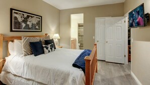 Un dormitorio con una cama, un mapa mundial en la pared, un televisor y una puerta que da a otra habitación.