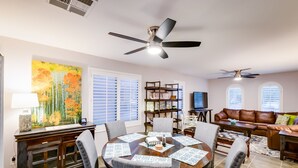 Un salón espacioso con comedor, chimenea y un amplio ventanal con persianas.