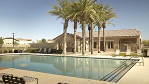 Una piscina con sillas de descanso y palmeras, rodeada de edificios con tejados de tejas.