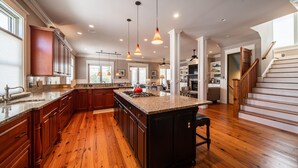 A spacious kitchen with wooden cabinets, a large island, and pendant lighting.