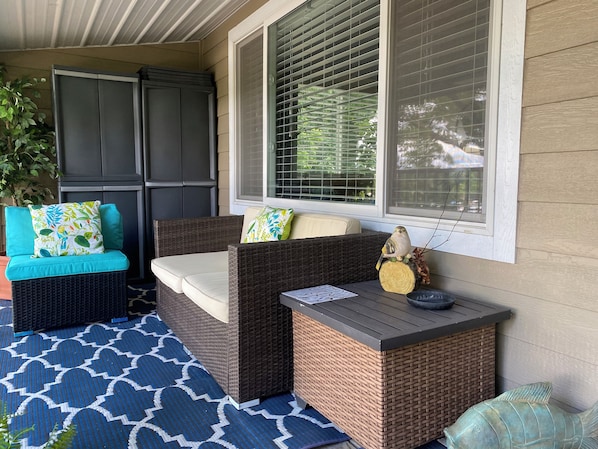 A covered porch with wicker furniture, a decorative fish sculpture, and a potted plant. - TROPICAL 2 BEDROOM LAKEVIEW CONDO CLOSE TO EVERYTHING! (Lake Ozark)