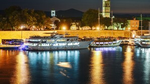 A waterfront marina with several boats docked, a prominent church tower, and a bus in the foreground. - Magic View Apartments (Zadar)