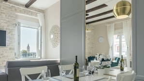 A dining area with a white table, chairs, and a large mirror. - Magic View Apartments (Zadar)