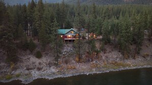 A cabin surrounded by dense forest and mountains.