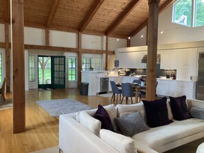 Relax in a spacious living area with a high ceiling, comfortable sofa, and adjacent kitchen.