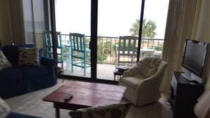 A living room with a blue sofa, a beige armchair, a wooden coffee table, and a television.