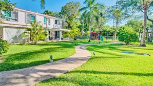 A house with a paved pathway leading to a covered porch, surrounded by lush greenery and palm trees. - Feb 25th onward avail 150Mbps Wifi 7 Bikes Beach Access Rare Find Contact me 🏖 (Playa del Carmen)