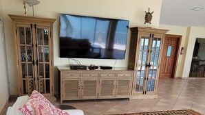 A living room with a large flat-screen TV, a sofa, a coffee table, and a patterned rug.