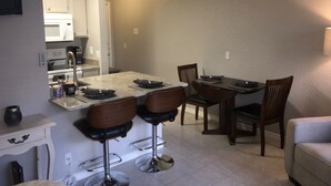 Une cuisine comprenant un coin repas, avec un îlot central, des tabourets de bar et une table à manger avec des chaises.