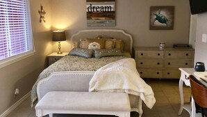 Une chambre à coucher comprenant un lit, des tables de chevet, un bureau et un ventilateur de plafond.